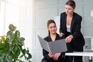 Young women leaders are checking financial statements from paper documents, dressed black suit.